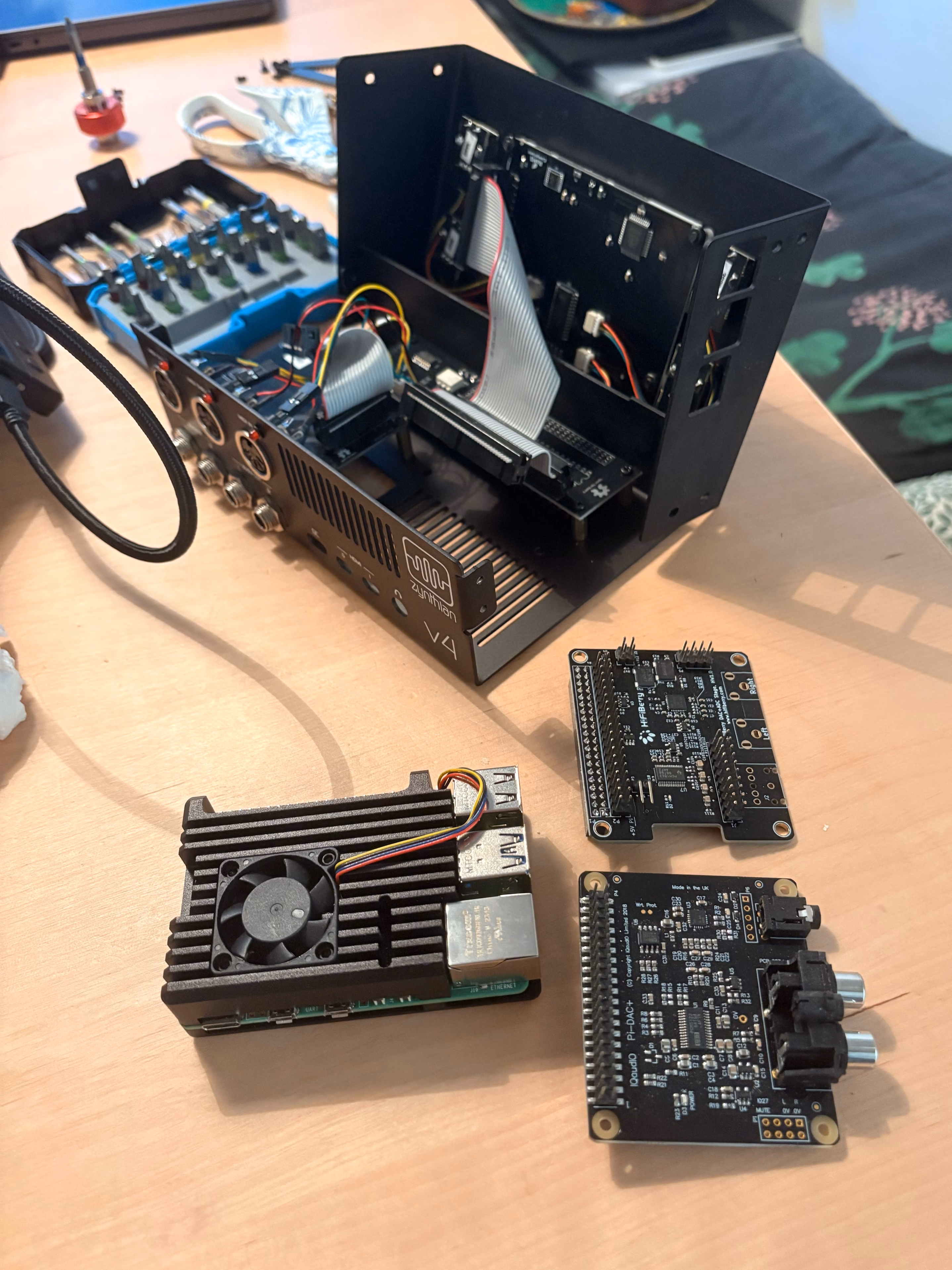 Zynthian case opened on a workbench, Pi 4 board and two soundcards laid out beside it
